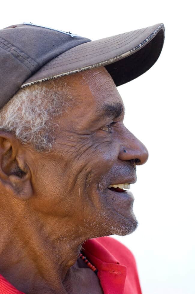 Aged man smiling, wearing a baseball cap, outdoor portrait, joyful expression, senior lifestyle photography.