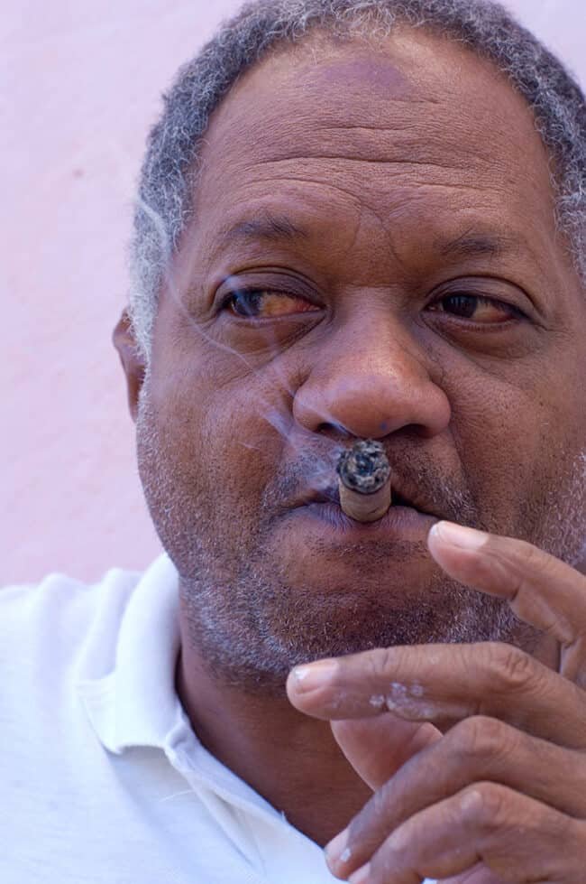 Aged man smoking cigar, close-up portrait, relaxed mature gentleman, casual photo.