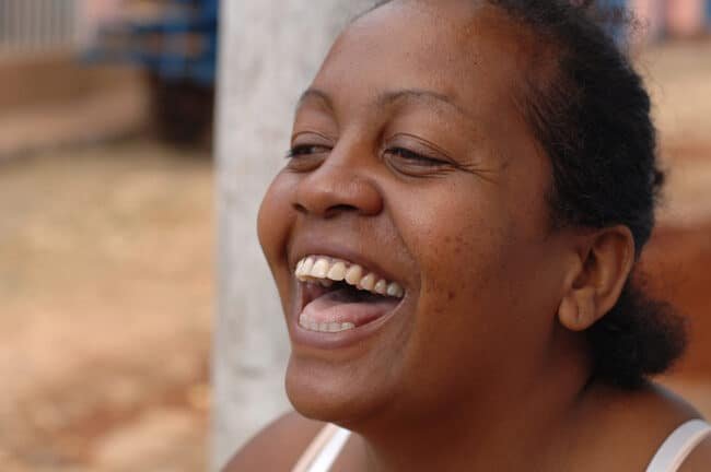 Joyful portrait of an African woman smiling outdoors, capturing happiness and vibrant personality.